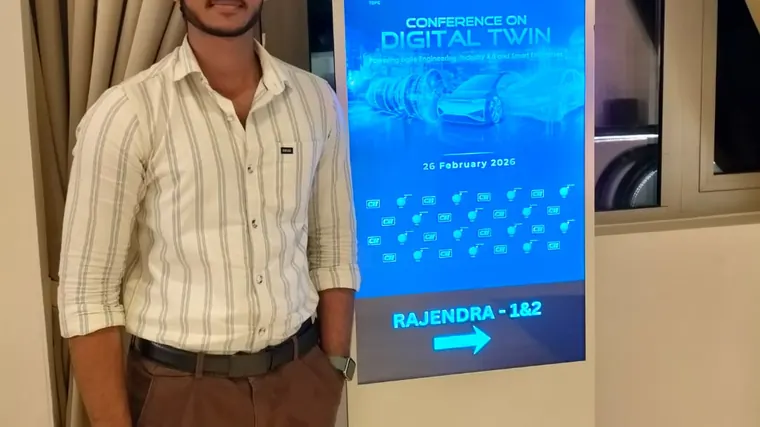 A person stands beside a blue event display.